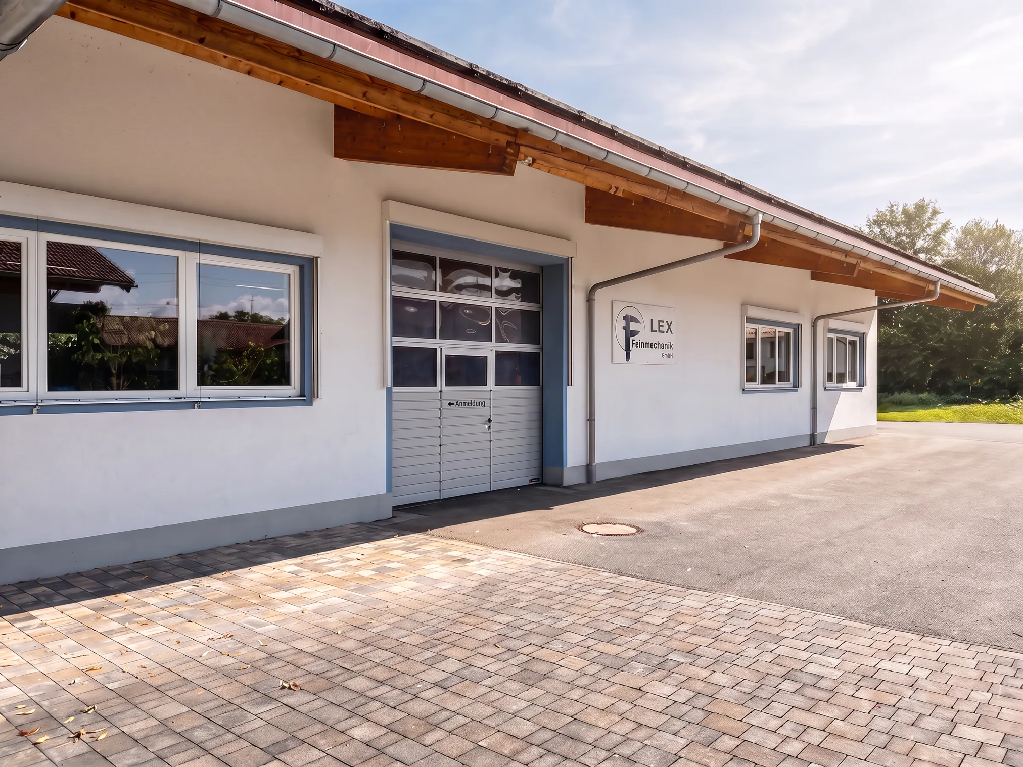Firmengebäude der LEX Feinmechanik GmbH mit Einfahrt und Firmenschild