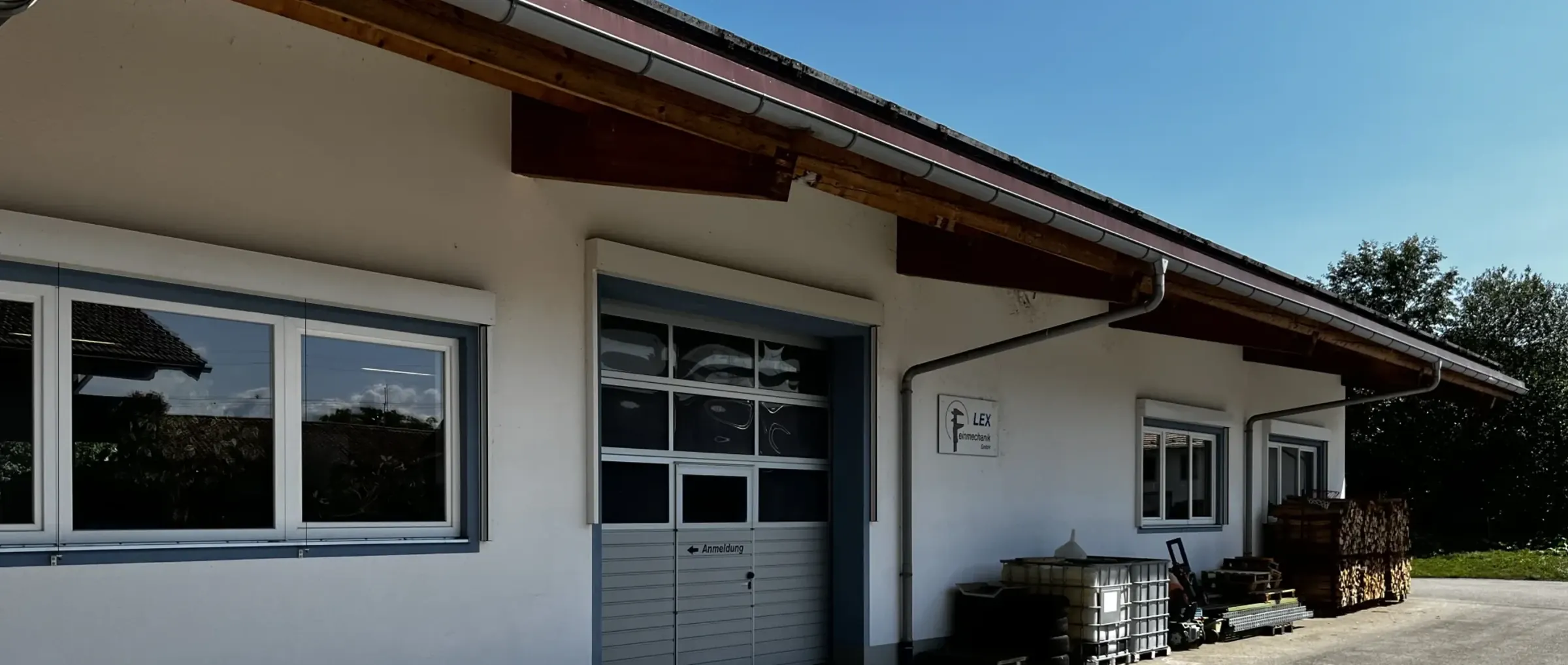 Firmengebäude von LEX Feinmechanik in Grabenstätt mit Einfahrt, Firmenschild und Anmeldung